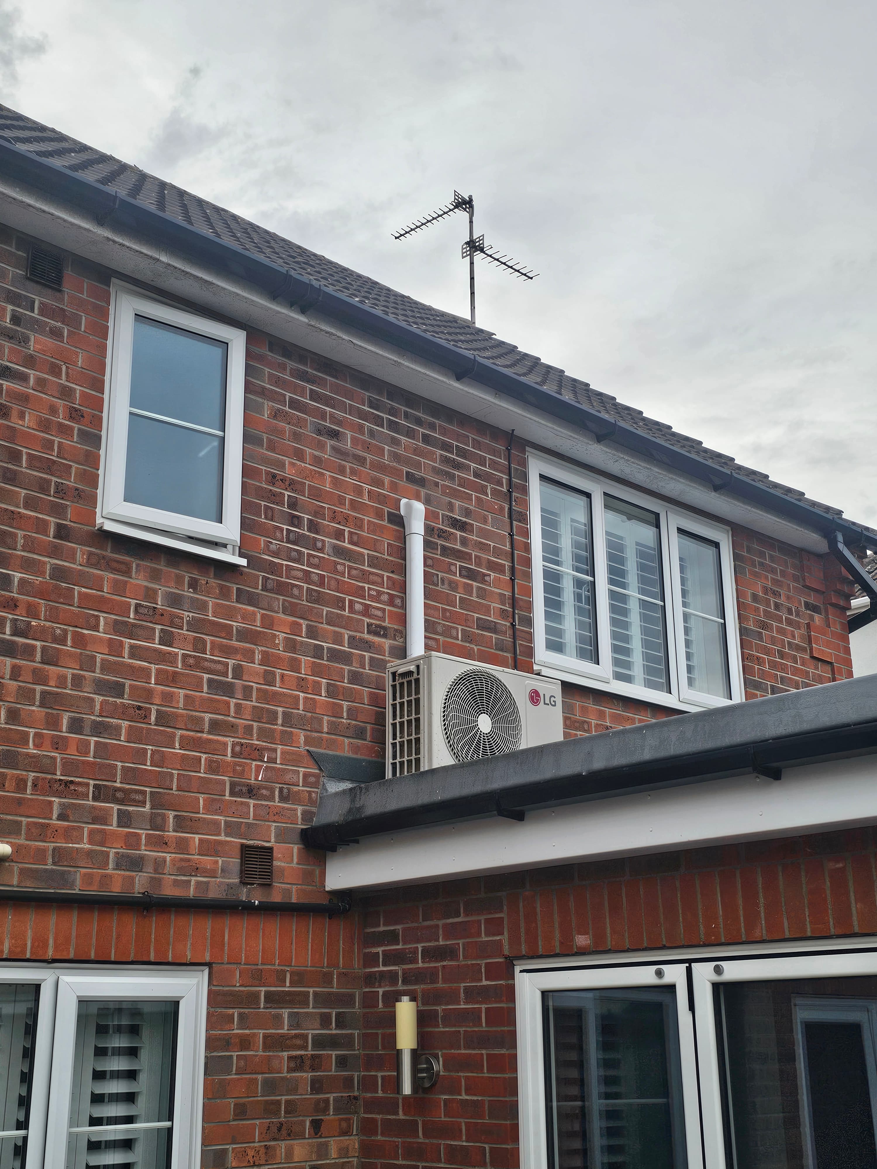 LG outdoor air conditioning condenser installed on a brick house