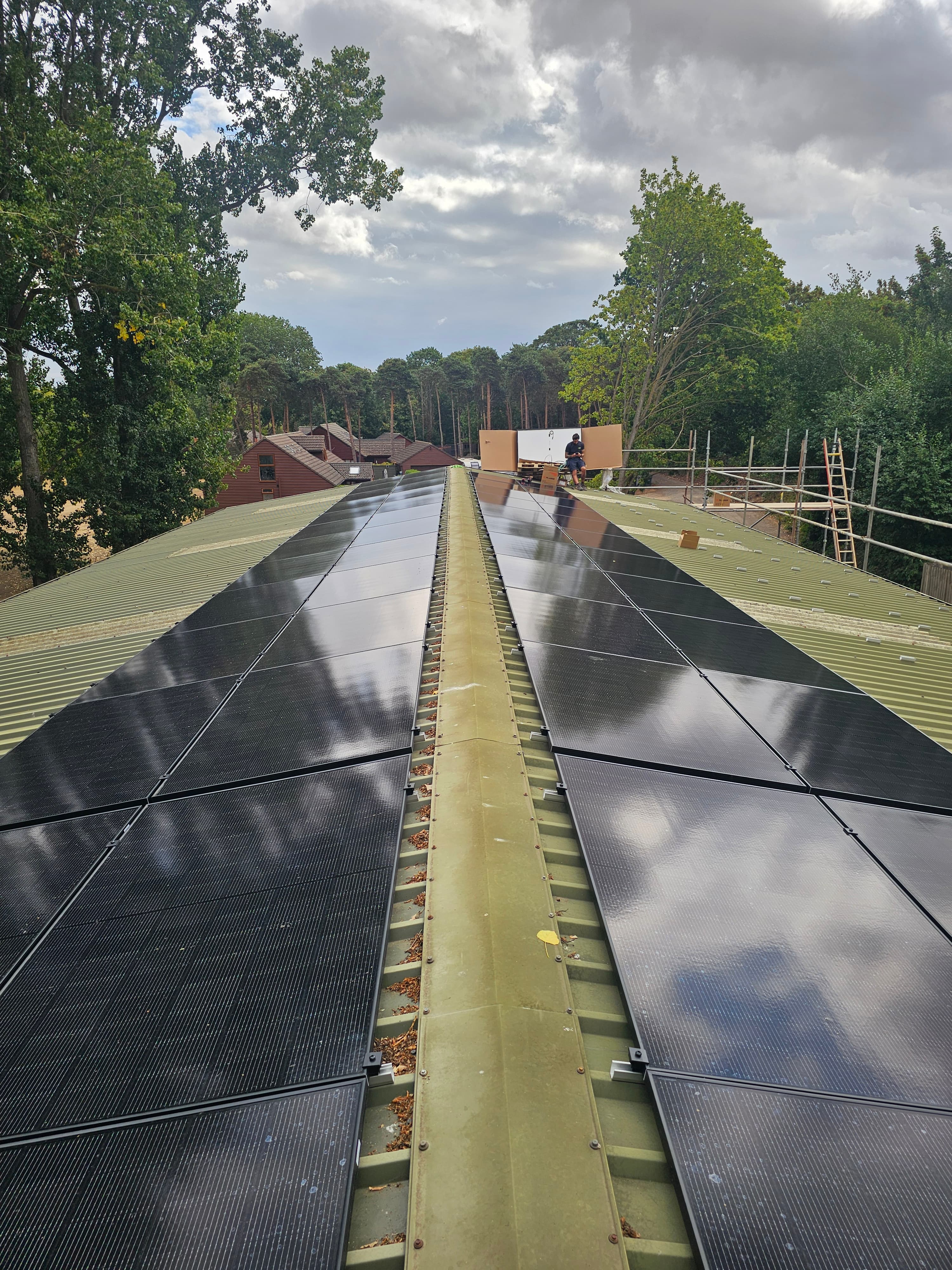 Large solar panel array installed on a green corrugated metal roof in rural Lincolnshire