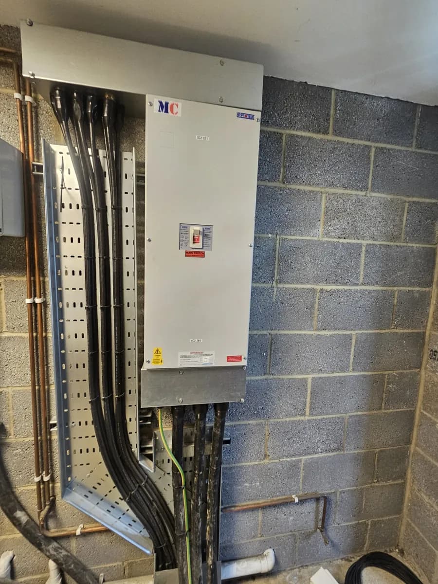 Large commercial main switch panel with heavy power cables on galvanised cable tray, part of a new incoming supply for a solar PV system in Lincolnshire