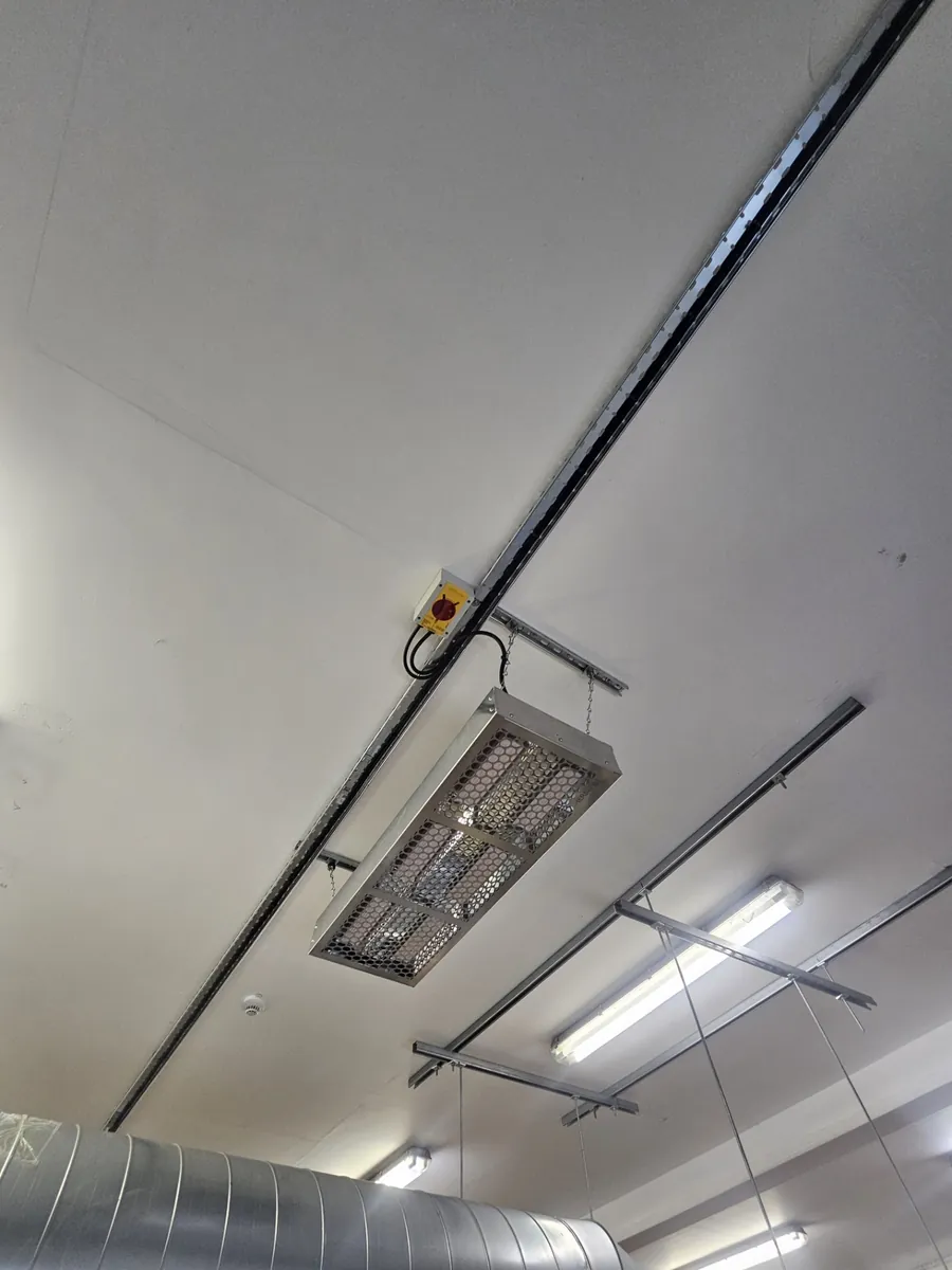 Close-up of a commercial electric radiant heater hung from unistrut with its own local rotary isolator, installed by PPM Electrical at Polyco in Bourne, Lincolnshire