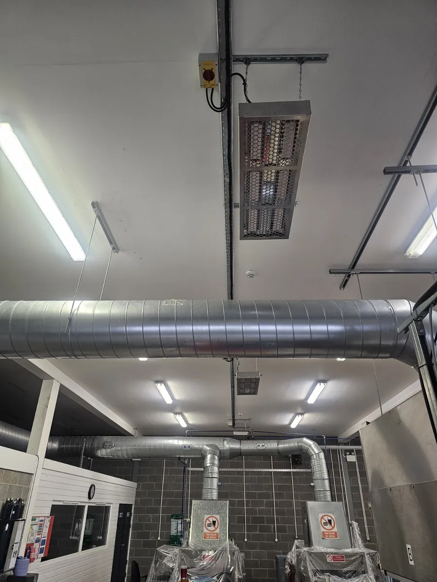 Ceiling-mounted 4.8 kW electric radiant heater with a local rotary isolator on unistrut above ductwork in a commercial building at Polyco in Bourne, Lincolnshire