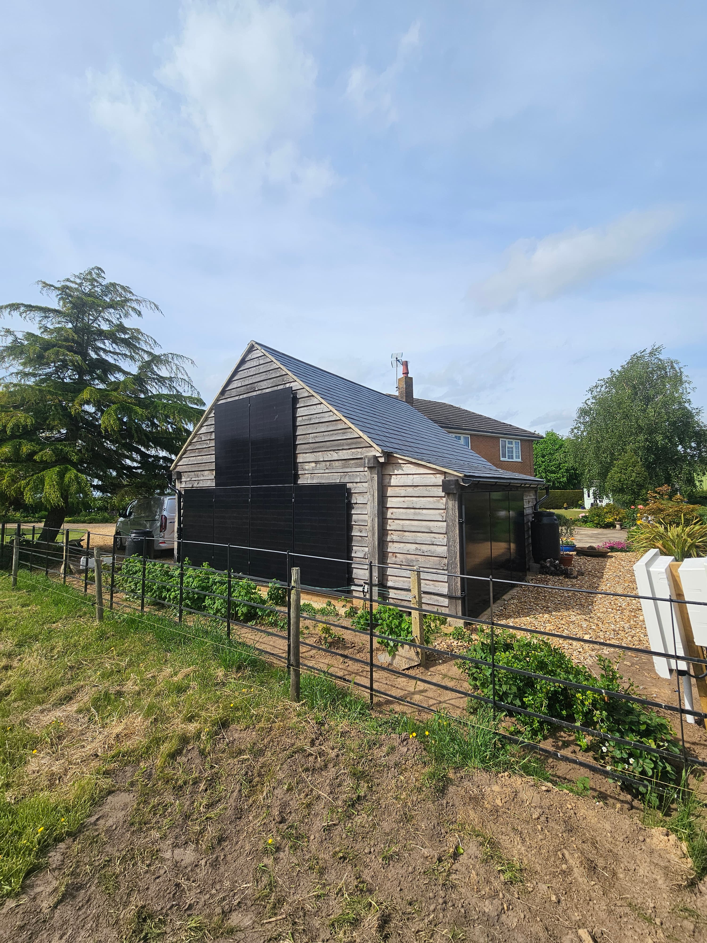 Solar PV panels installed on a garden outbuilding with brick home in background