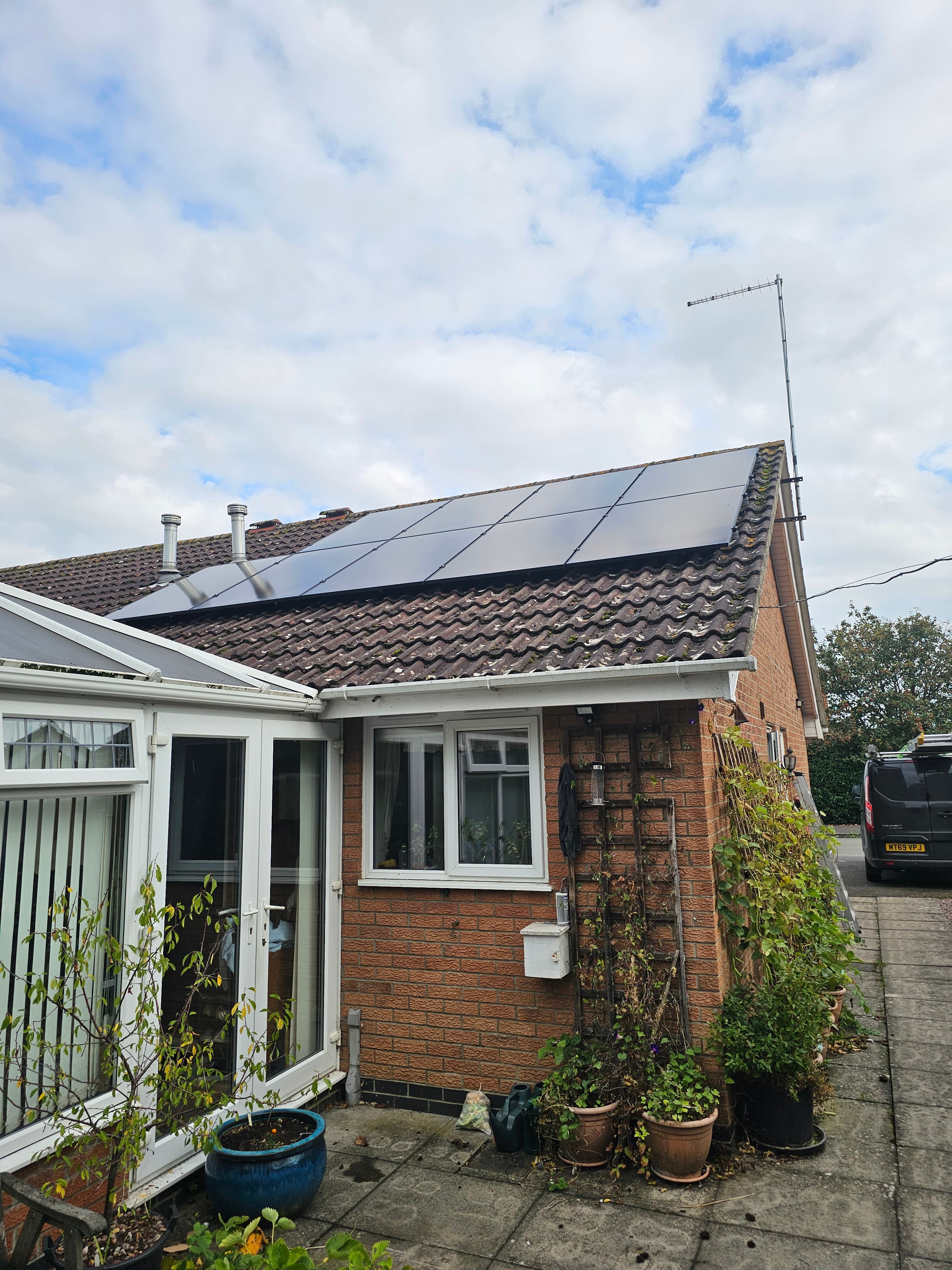 Solar PV panels installed on a brick house roof with inverter mounted on the wall