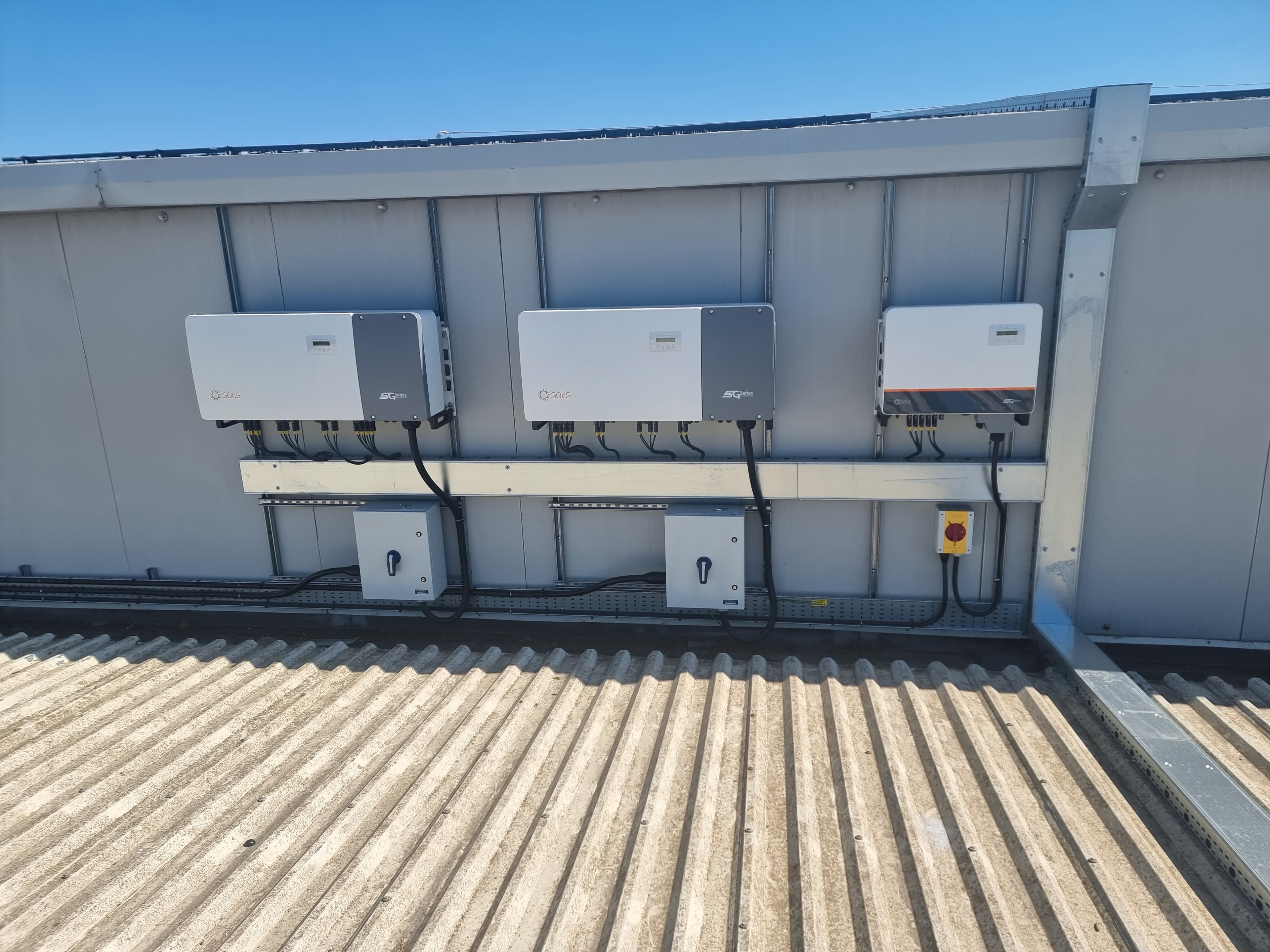 Three Solis solar inverters and electrical isolators mounted on a building exterior